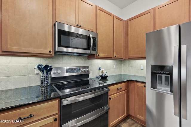 kitchen with decorative backsplash, dark stone counters, wood finished floors, and appliances with stainless steel finishes