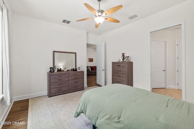 bedroom featuring a ceiling fan, wood finished floors, baseboards, and visible vents