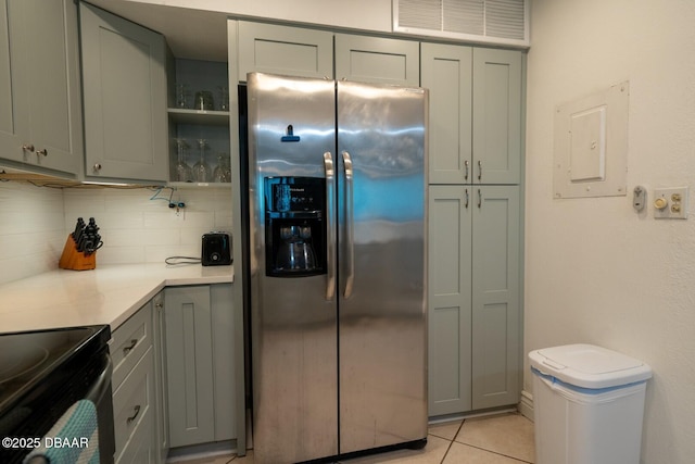 kitchen with light tile patterned flooring, stainless steel fridge with ice dispenser, electric panel, gray cabinets, and decorative backsplash