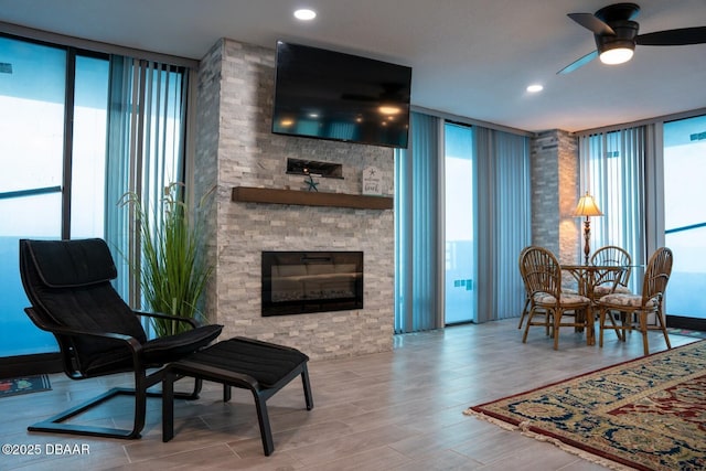 living room with a stone fireplace, a wealth of natural light, and floor to ceiling windows