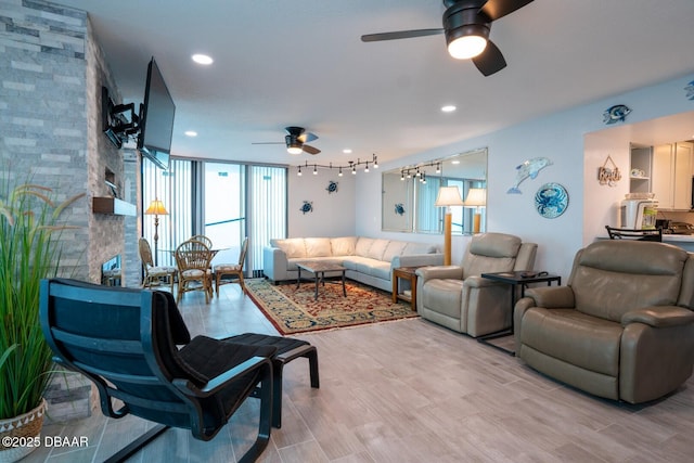 living room featuring ceiling fan, track lighting, a wall of windows, and light wood-type flooring