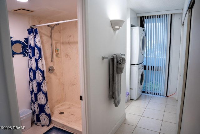 bathroom featuring curtained shower, tile patterned floors, and stacked washing maching and dryer