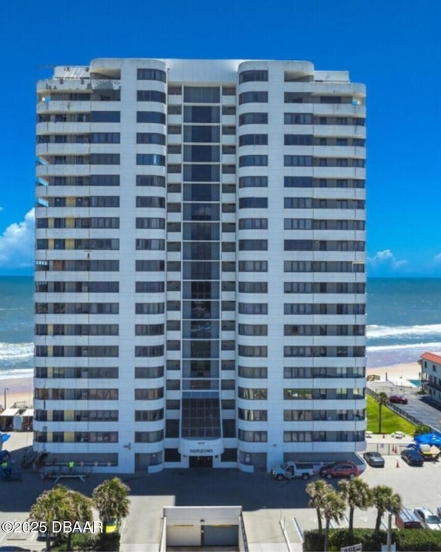 view of building exterior featuring a water view and a view of the beach