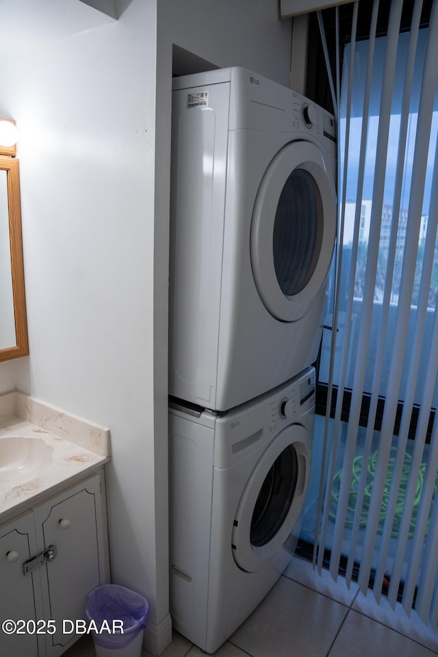 laundry room featuring stacked washer and dryer and light tile patterned floors