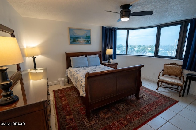 tiled bedroom with ceiling fan and a textured ceiling