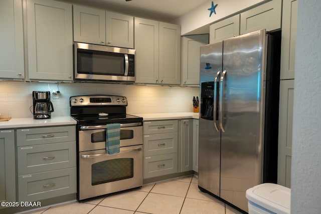 kitchen with stainless steel appliances, gray cabinets, and decorative backsplash