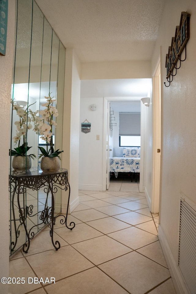 hallway with a textured ceiling and light tile patterned flooring