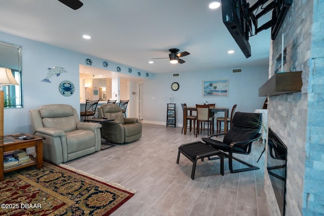 living room featuring a large fireplace and ceiling fan