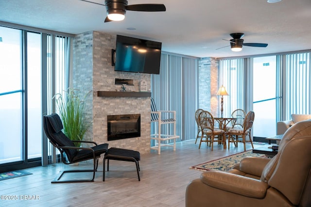 living room featuring expansive windows, plenty of natural light, a large fireplace, and light hardwood / wood-style flooring