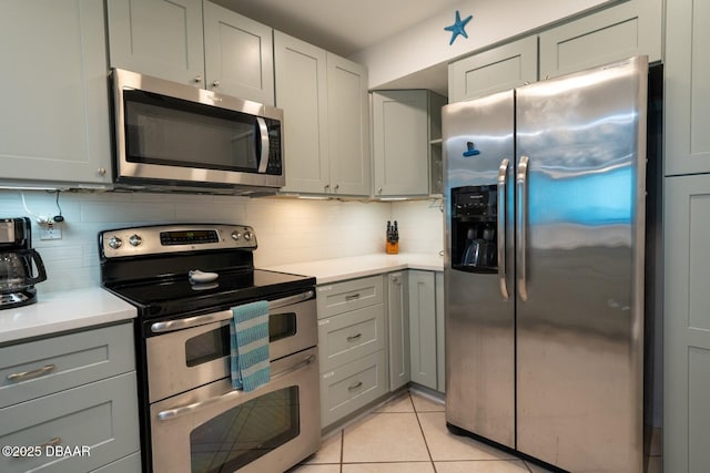 kitchen with backsplash, light tile patterned floors, gray cabinets, and appliances with stainless steel finishes