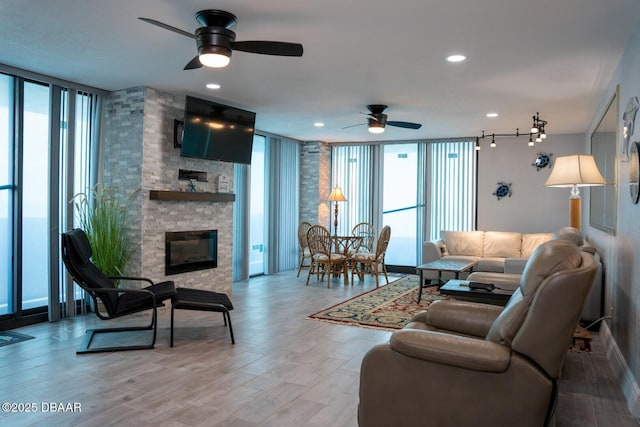 living room with a wall of windows, a healthy amount of sunlight, a stone fireplace, and light wood-type flooring