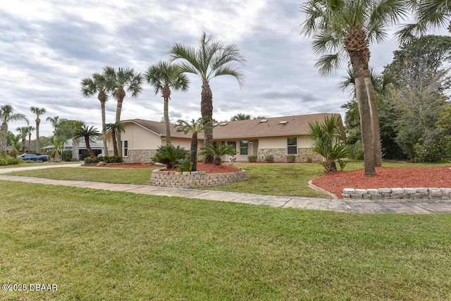 view of front of home featuring stone siding, a front yard, and stucco siding