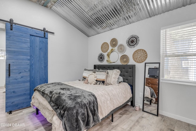 bedroom featuring wood-type flooring, a barn door, and lofted ceiling