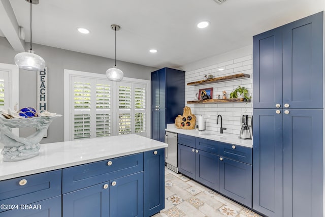 kitchen featuring pendant lighting, decorative backsplash, sink, and blue cabinets