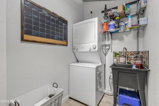 clothes washing area featuring stacked washing maching and dryer and light wood-type flooring