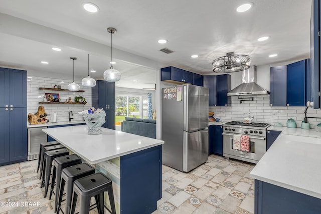 kitchen featuring stainless steel appliances, decorative backsplash, a breakfast bar area, blue cabinets, and wall chimney exhaust hood