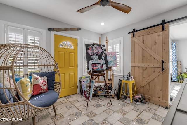 interior space with a barn door and ceiling fan