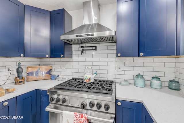 kitchen with blue cabinetry, stainless steel range, wall chimney exhaust hood, and backsplash