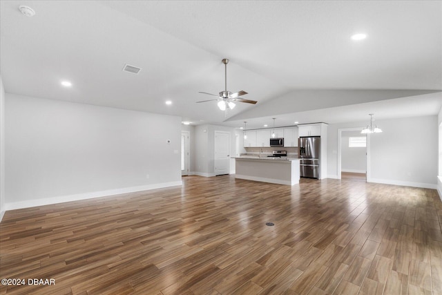 unfurnished living room with hardwood / wood-style flooring, ceiling fan with notable chandelier, and vaulted ceiling