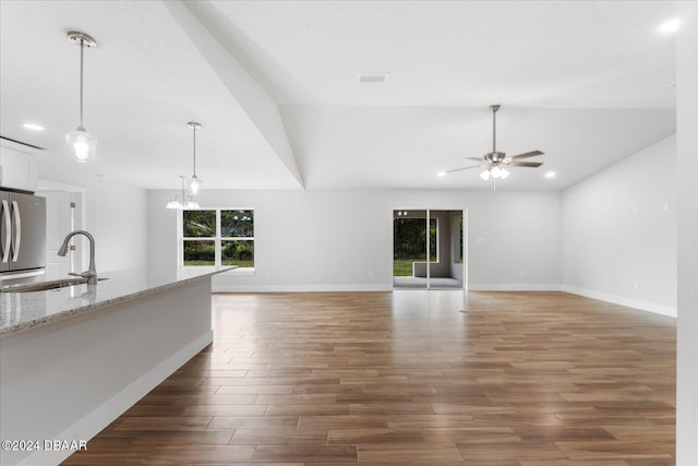 unfurnished living room with dark hardwood / wood-style flooring, sink, a healthy amount of sunlight, and ceiling fan with notable chandelier