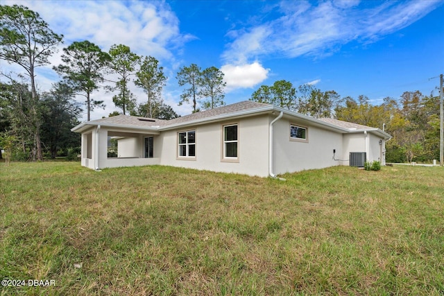 back of property featuring a lawn and central AC