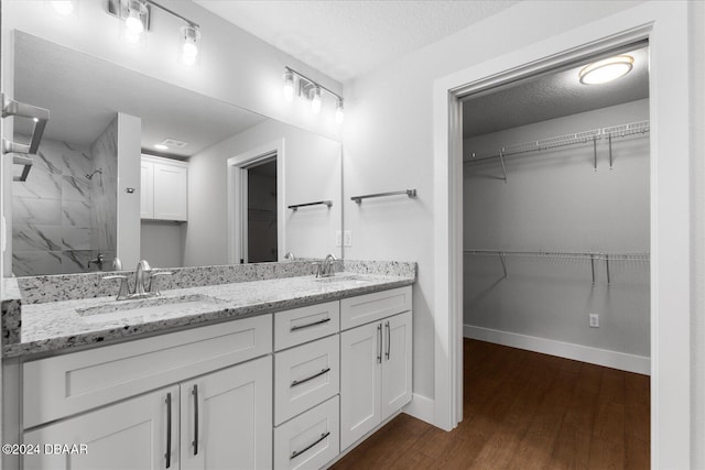 bathroom with vanity, wood-type flooring, a textured ceiling, and tiled shower