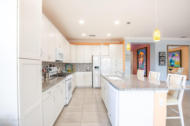 kitchen with white cabinetry, white appliances, a breakfast bar area, and a center island with sink