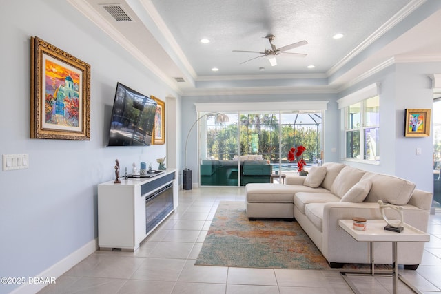 tiled living room with crown molding, ceiling fan, a raised ceiling, and a textured ceiling