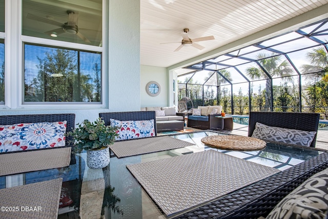 view of patio featuring ceiling fan, outdoor lounge area, and glass enclosure