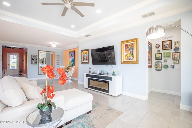 tiled living room with ornamental molding, a raised ceiling, and ceiling fan