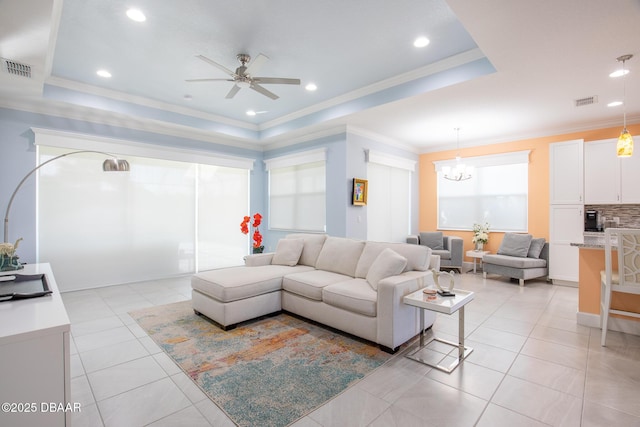 tiled living room featuring crown molding, a raised ceiling, and ceiling fan with notable chandelier