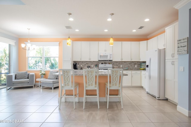 kitchen featuring a breakfast bar area, white cabinetry, a kitchen island, white appliances, and a healthy amount of sunlight