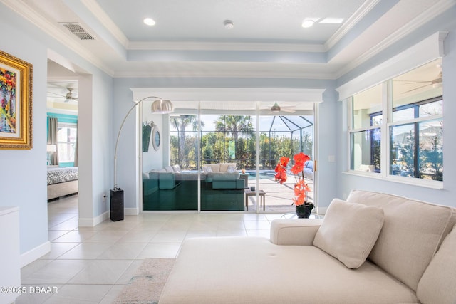 tiled living room with crown molding, ceiling fan, and a raised ceiling