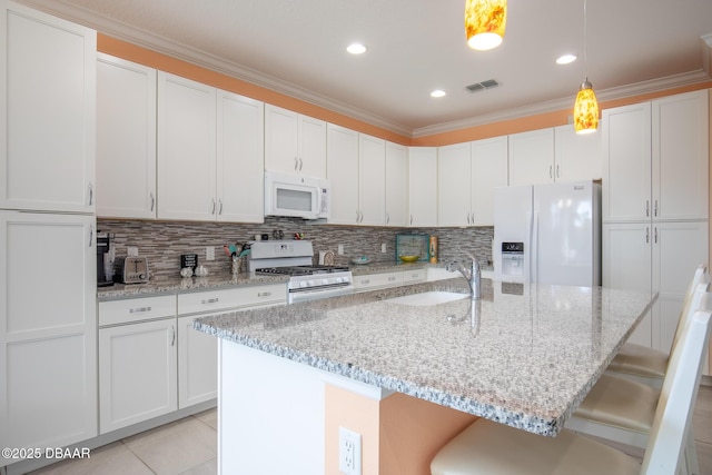 kitchen with sink, white appliances, a kitchen breakfast bar, white cabinets, and decorative light fixtures