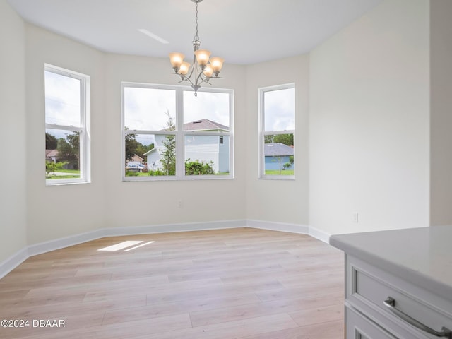 unfurnished dining area featuring light wood-type flooring, an inviting chandelier, and a healthy amount of sunlight