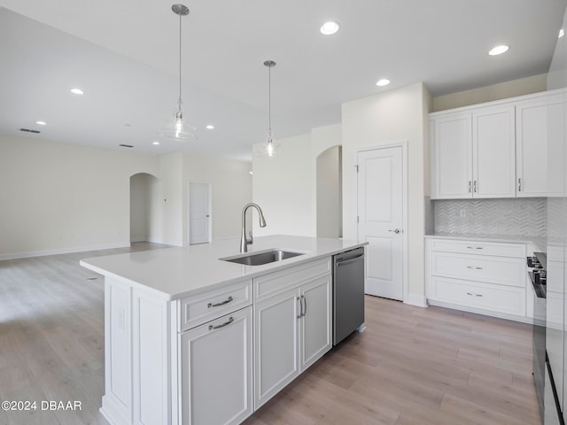 kitchen with white cabinets, stainless steel dishwasher, a center island with sink, and sink