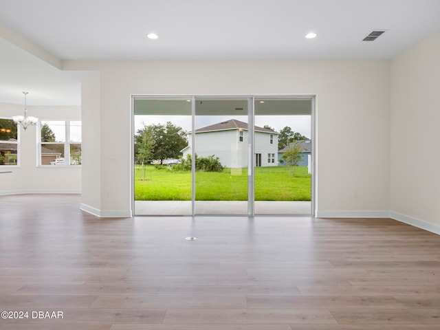 empty room featuring light hardwood / wood-style floors and an inviting chandelier