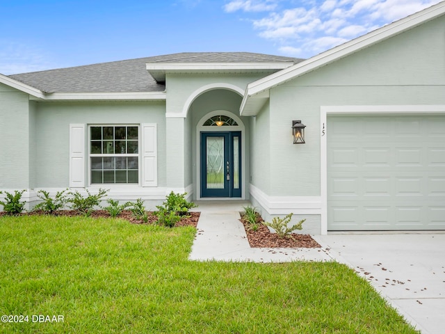 view of exterior entry with a garage and a yard