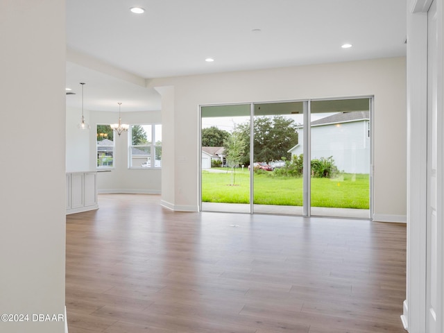 spare room featuring plenty of natural light, light wood-type flooring, and a notable chandelier