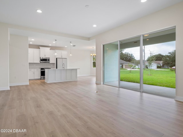 unfurnished living room featuring light hardwood / wood-style flooring and a notable chandelier