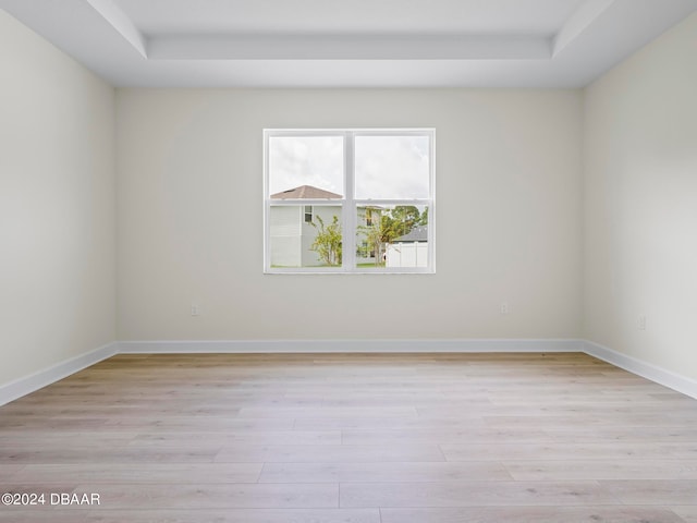 spare room with light hardwood / wood-style floors and a tray ceiling