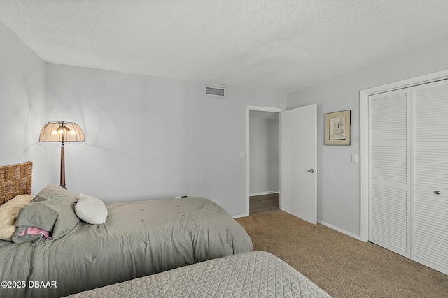 carpeted bedroom with a textured ceiling, a closet, visible vents, and baseboards