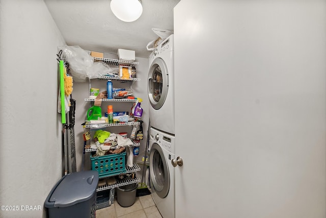 clothes washing area with laundry area, tile patterned flooring, and stacked washer and clothes dryer