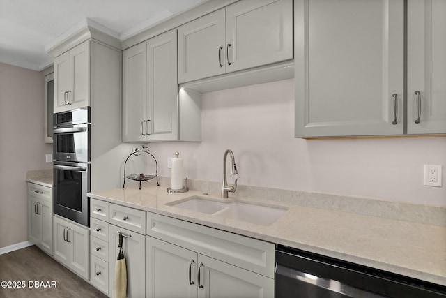 kitchen with dark wood finished floors, appliances with stainless steel finishes, white cabinetry, a sink, and light stone countertops