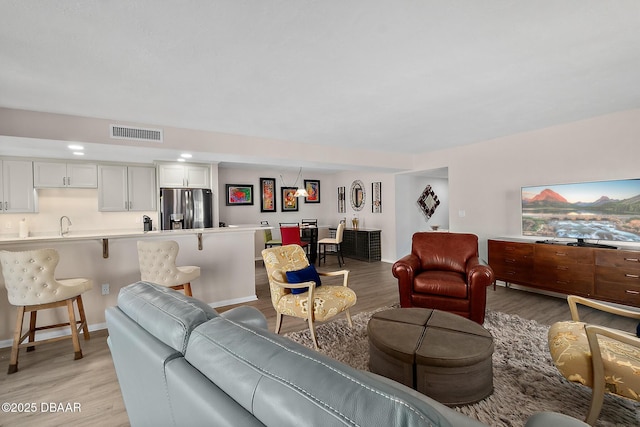 living area featuring light wood-style floors, visible vents, and baseboards