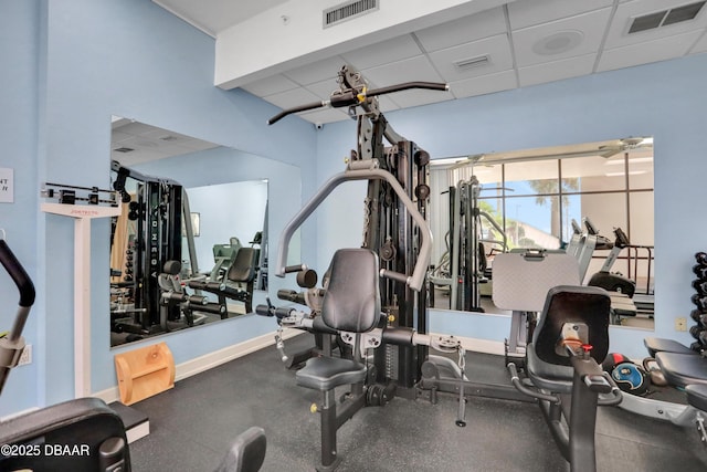 gym featuring a paneled ceiling, baseboards, and visible vents