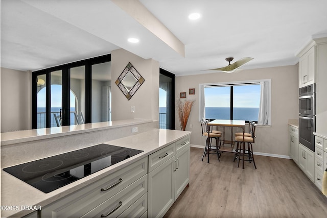 kitchen featuring light countertops, light wood-style flooring, double oven, and black electric cooktop