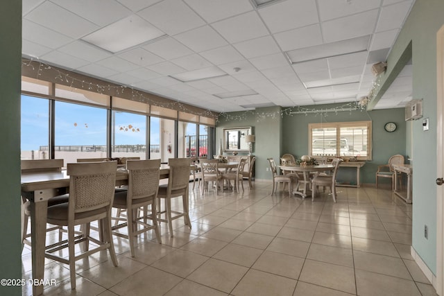 dining space featuring baseboards, a paneled ceiling, and tile patterned floors