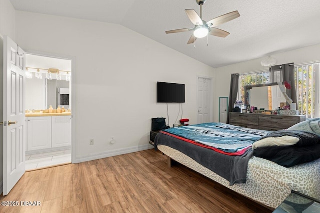 bedroom featuring vaulted ceiling, ensuite bathroom, hardwood / wood-style flooring, ceiling fan, and a textured ceiling