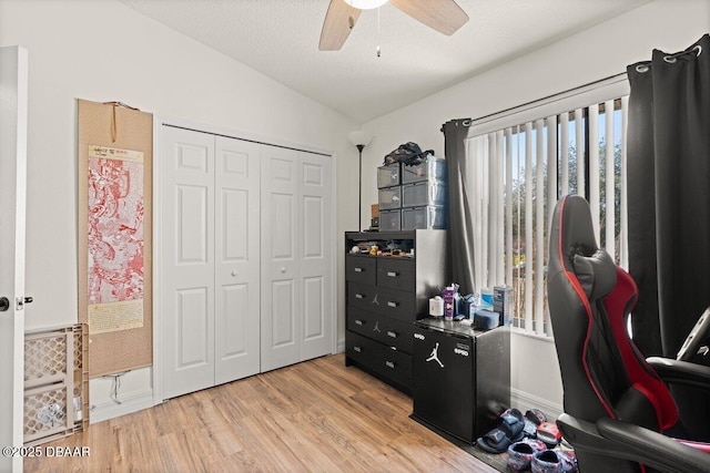 interior space featuring ceiling fan, lofted ceiling, a textured ceiling, and light wood-type flooring